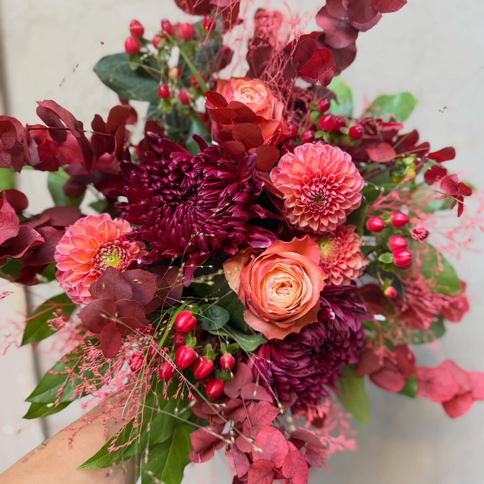 Composition automnale, chrysanthème pourpre, dahlias corail, roses saumon et baies rouges