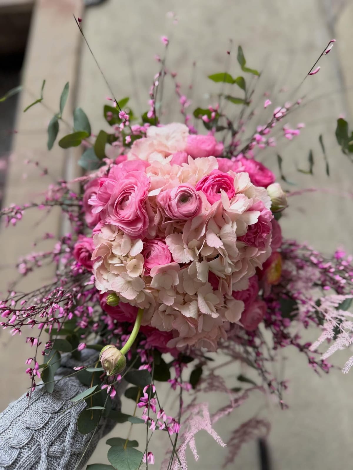 Bouquet de renoncules roses et pâles, avec des branches fleuries