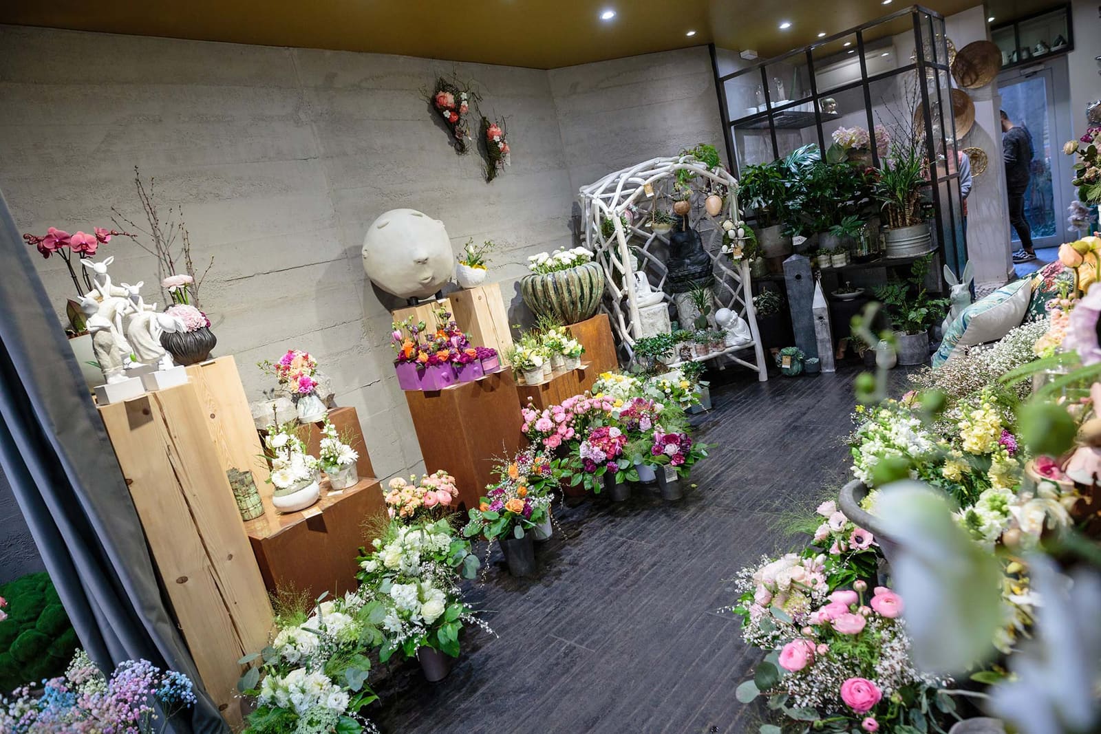 Intérieur de la boutique, compositions florales posées sur des présentoirs en bois